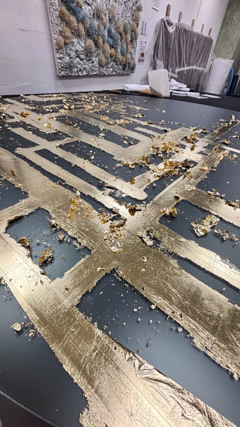 Application de feuille d’or sur un miroir artistique dans l’atelier d’Amandine Mangenot, révélant le travail de matière et la compososition.