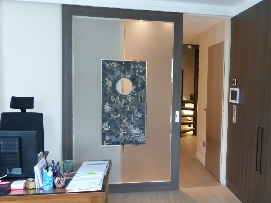 Porte artistique en verre gravé avec cercle central intégré dans un espace de bureau – projet Club Lounge